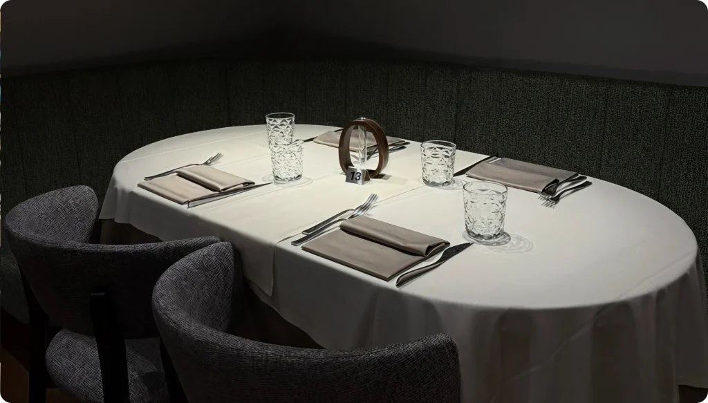 Un tavolo da pranzo splendidamente apparecchiato con stoviglie eleganti e luci d'ambiente soffuse in un ristorante contemporaneo.